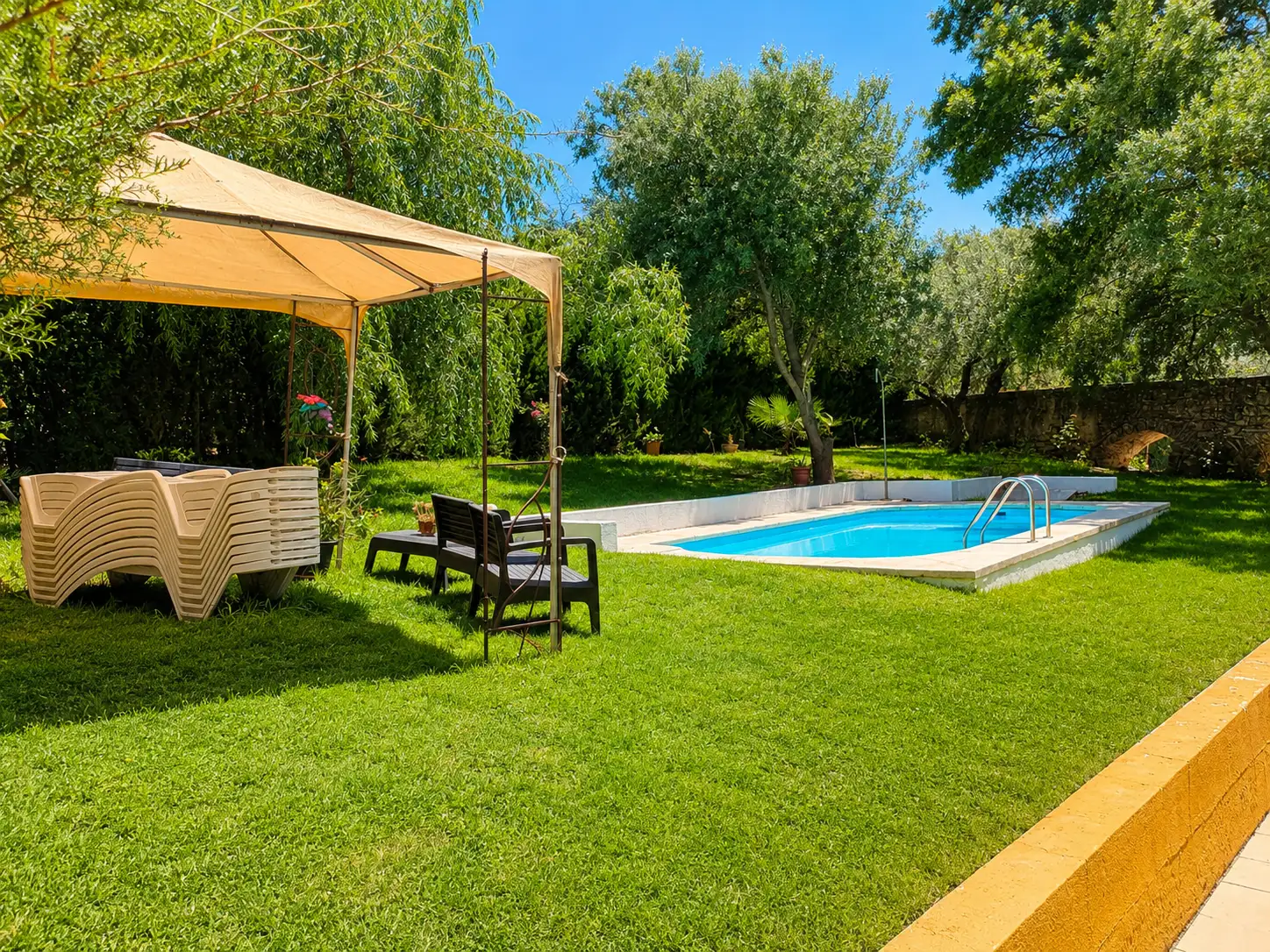 Jardín arbolado y piscina exterior del cortijo