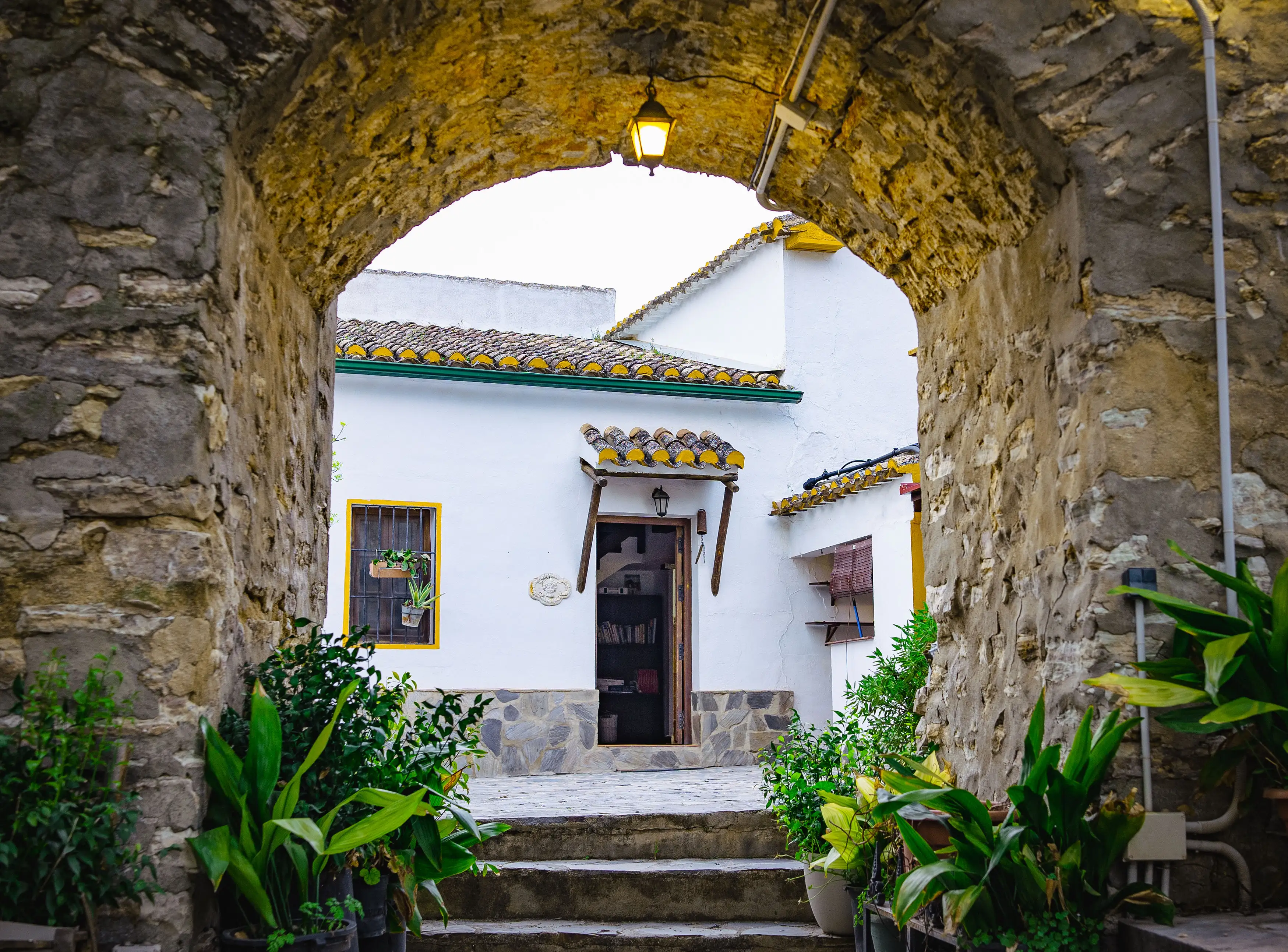 Arco de piedra enmarcando la fachada blanca del cortijo