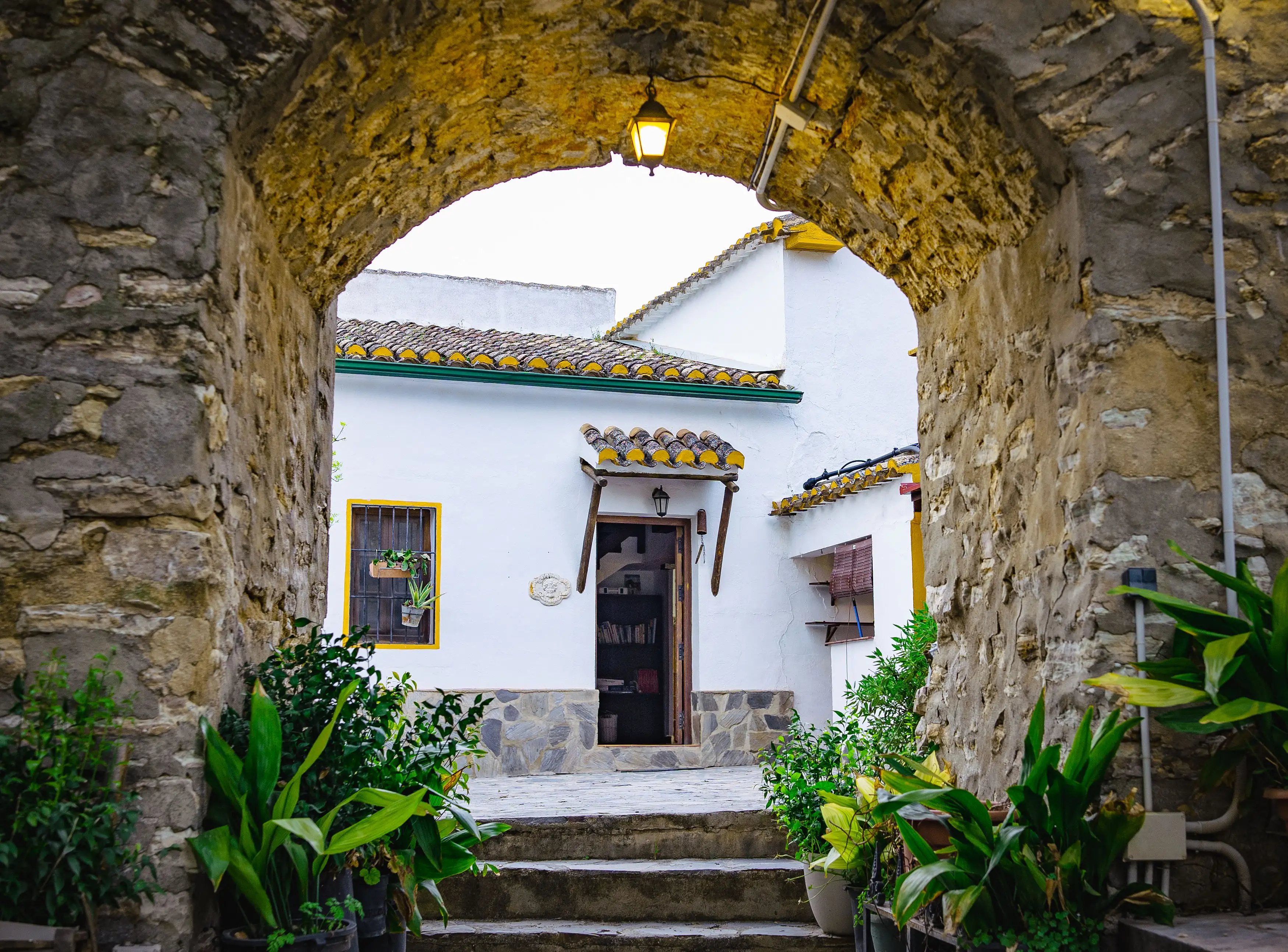 Arco de piedra enmarcando la fachada blanca del cortijo